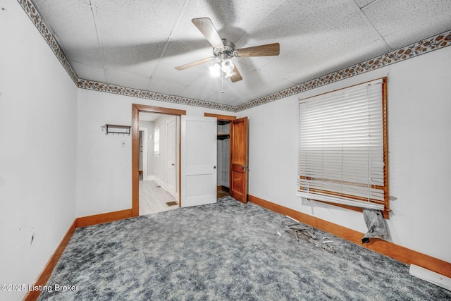 carpeted bedroom with a drop ceiling, a ceiling fan, and baseboards