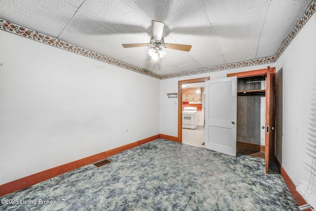unfurnished bedroom with ceiling fan, visible vents, carpet, baseboards, and a drop ceiling