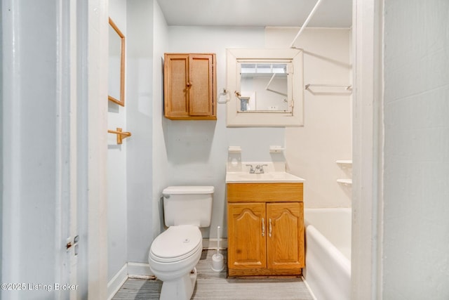 bathroom with toilet, wood finished floors, vanity, and baseboards