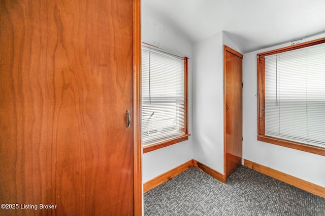carpeted spare room with baseboards and vaulted ceiling