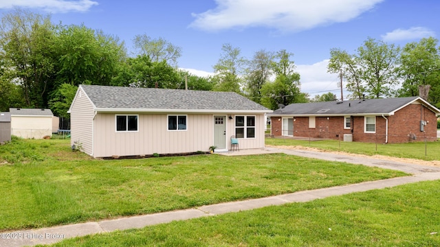 ranch-style house with a front lawn, fence, and an outbuilding