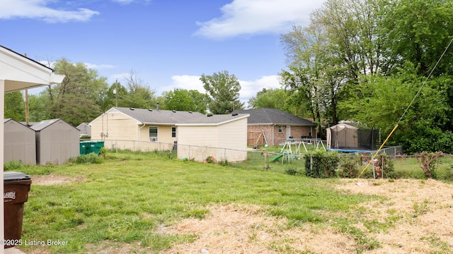 view of yard featuring fence, a storage unit, a trampoline, and an outdoor structure