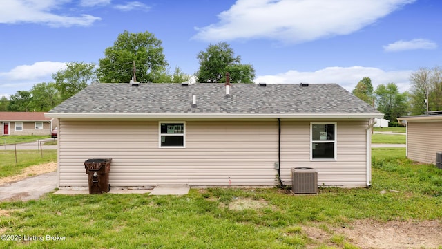 rear view of property with a lawn, fence, a shingled roof, and cooling unit