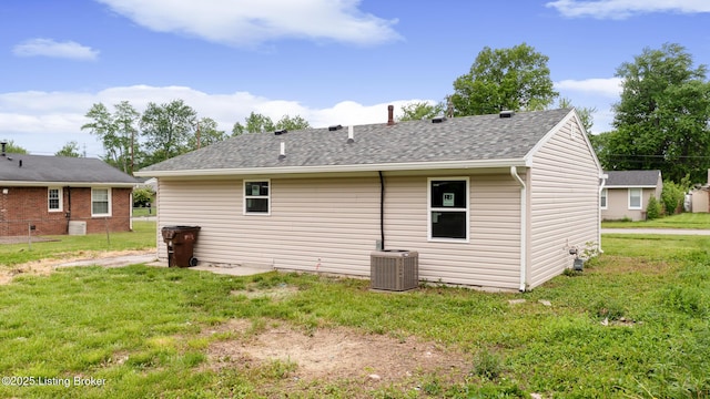 rear view of house featuring roof with shingles, a yard, and cooling unit
