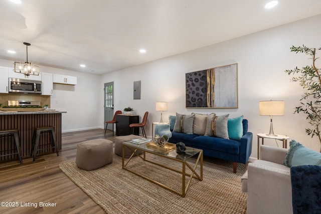 living area featuring recessed lighting, baseboards, wood finished floors, and electric panel