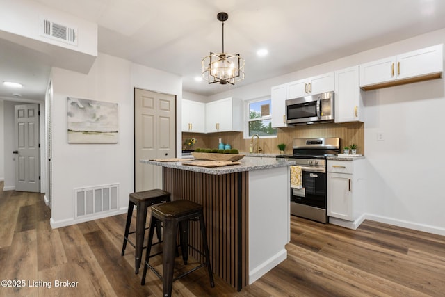kitchen featuring visible vents, dark wood-style flooring, a center island, white cabinetry, and stainless steel appliances