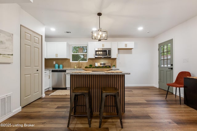 kitchen featuring decorative backsplash, visible vents, a center island, white cabinets, and stainless steel appliances