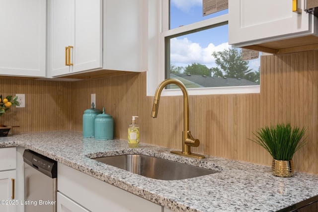 details with light stone counters, a sink, white cabinetry, and dishwasher