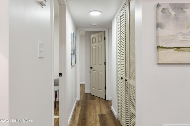 corridor with baseboards and wood finished floors