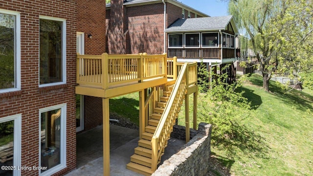view of playground featuring stairs, a wooden deck, a sunroom, a patio area, and a lawn