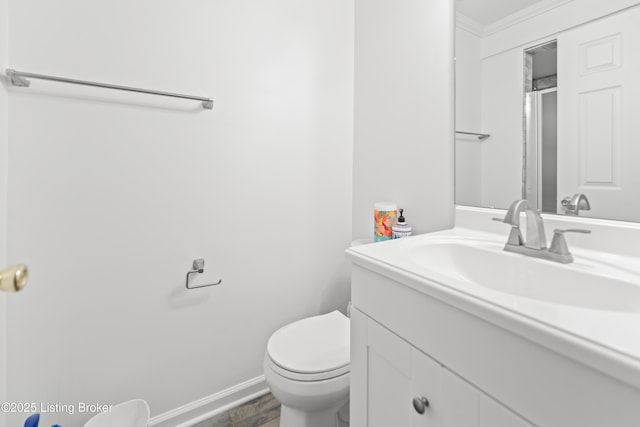 bathroom featuring vanity, toilet, baseboards, ornamental molding, and wood finished floors