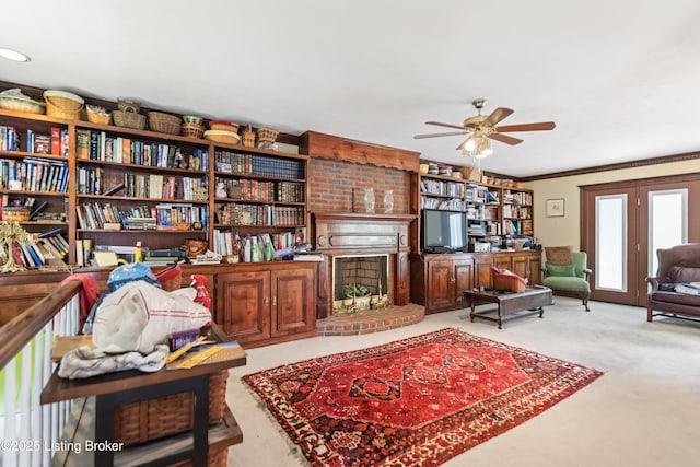 living area with crown molding, a ceiling fan, and light colored carpet