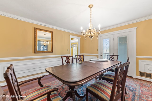 dining area with crown molding, an inviting chandelier, wainscoting, and visible vents