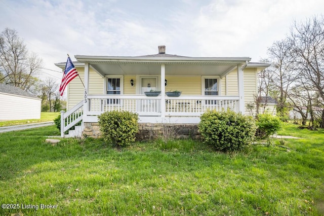 bungalow-style house featuring a front lawn, covered porch, and a chimney