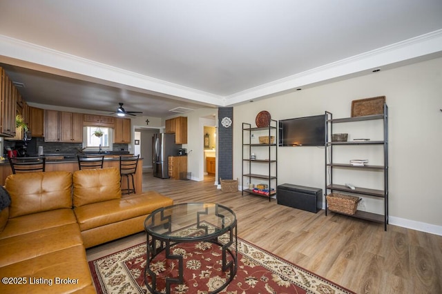 living area with a ceiling fan, light wood-style flooring, and baseboards