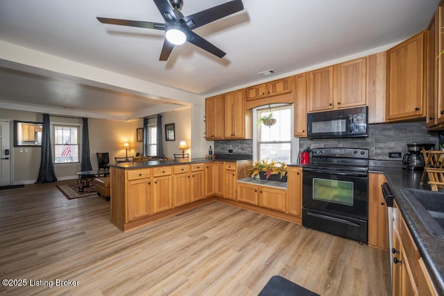 kitchen with black appliances, dark countertops, a peninsula, and decorative backsplash