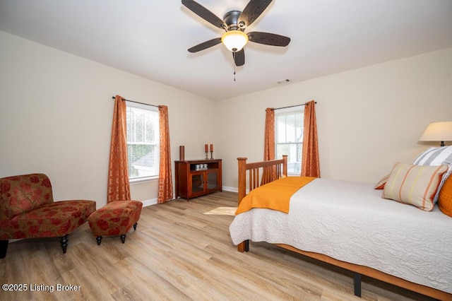 bedroom featuring a ceiling fan, visible vents, wood finished floors, and baseboards