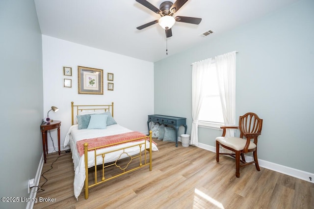 bedroom featuring wood finished floors, a ceiling fan, visible vents, and baseboards