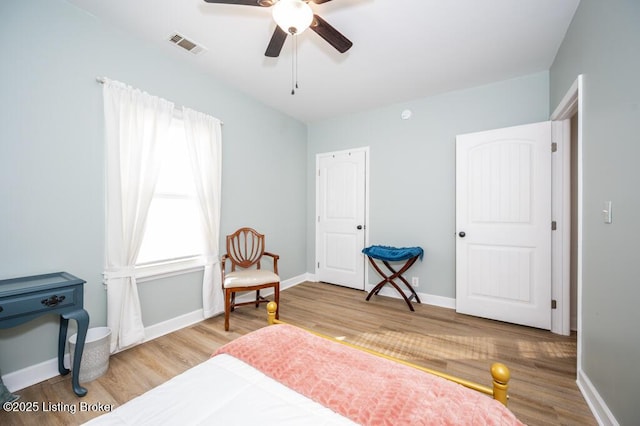 bedroom featuring wood finished floors, a ceiling fan, visible vents, and baseboards