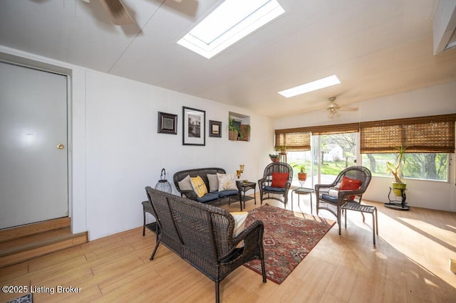 living room with a healthy amount of sunlight, wood finished floors, ceiling fan, and lofted ceiling with skylight