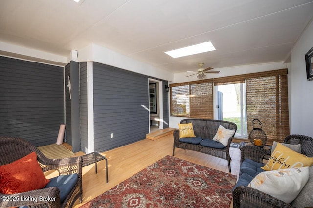 living area with wood finished floors, ceiling fan, and a skylight