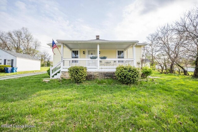 view of front of home with a porch, a front lawn, and a chimney
