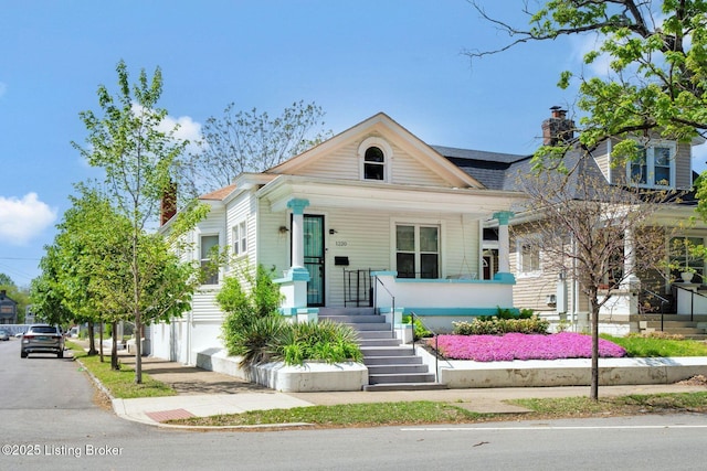 shotgun-style home with covered porch and a chimney
