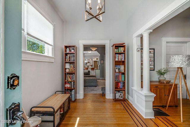 hall featuring a chandelier, decorative columns, and light wood-type flooring