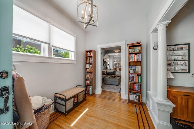 interior space with ornate columns, an inviting chandelier, and light wood finished floors