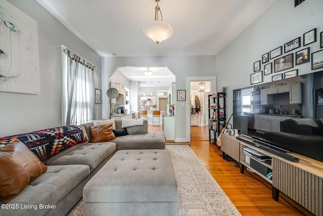 living room featuring arched walkways and light wood-style flooring