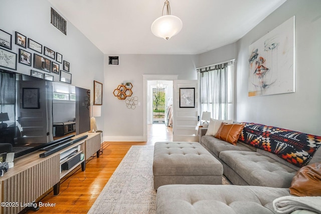 living area with light wood-style floors, visible vents, and a wealth of natural light