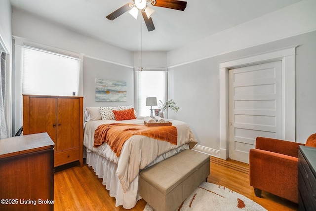 bedroom with light wood finished floors, ceiling fan, and multiple windows