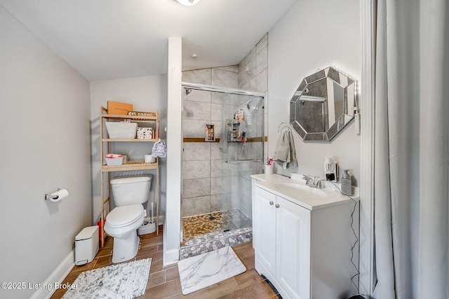bathroom featuring vanity, toilet, baseboards, wood finished floors, and a stall shower