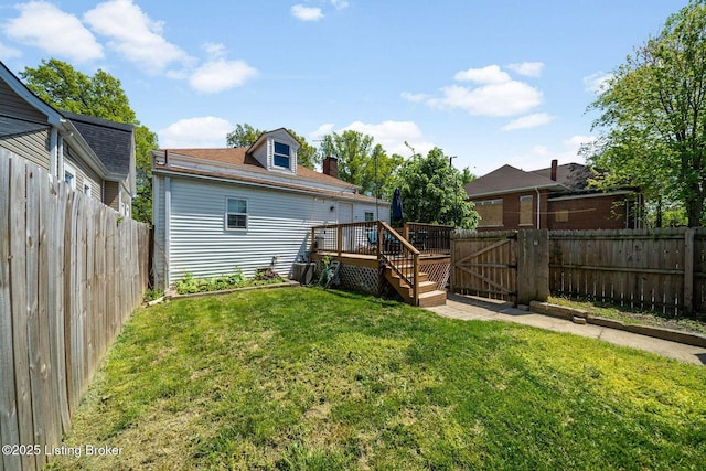 back of property with a fenced backyard, a wooden deck, a yard, and a gate