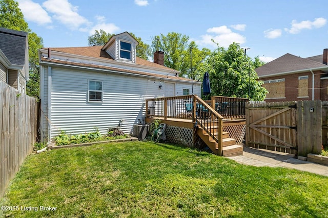 back of house with a fenced backyard, a gate, a yard, and a deck