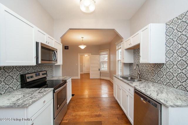 kitchen with a sink, appliances with stainless steel finishes, wood finished floors, and white cabinetry
