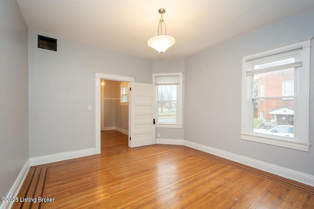 unfurnished room featuring baseboards, visible vents, and light wood-style flooring