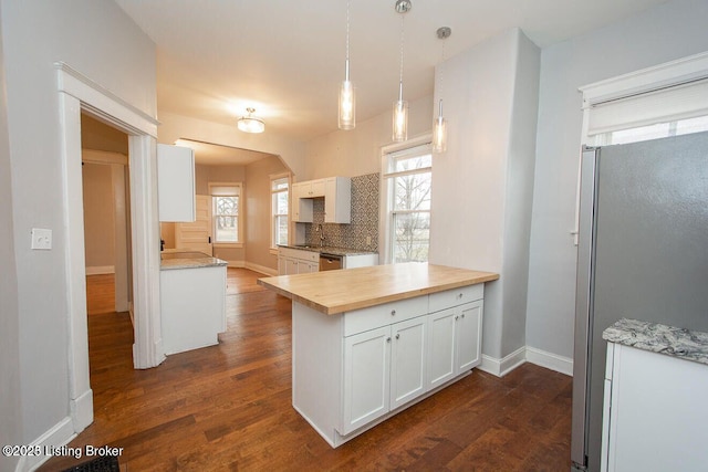 kitchen with white cabinets, appliances with stainless steel finishes, a peninsula, baseboards, and dark wood-type flooring