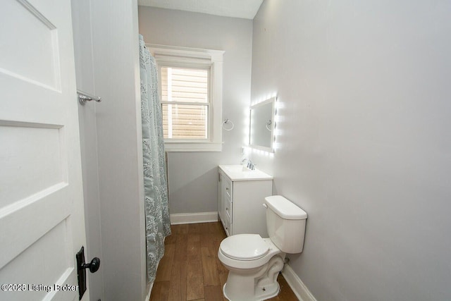 full bathroom with vanity, wood finished floors, curtained shower, toilet, and baseboards