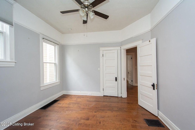 unfurnished bedroom with ceiling fan, baseboards, visible vents, and wood finished floors