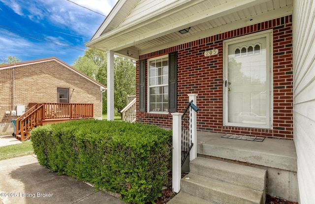 property entrance with brick siding and a porch