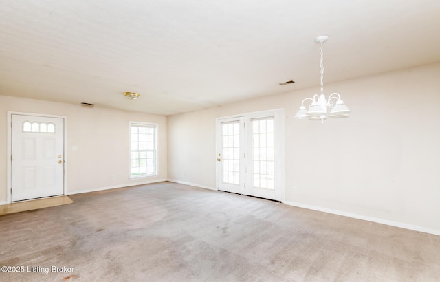 interior space featuring baseboards, visible vents, carpet flooring, and a notable chandelier