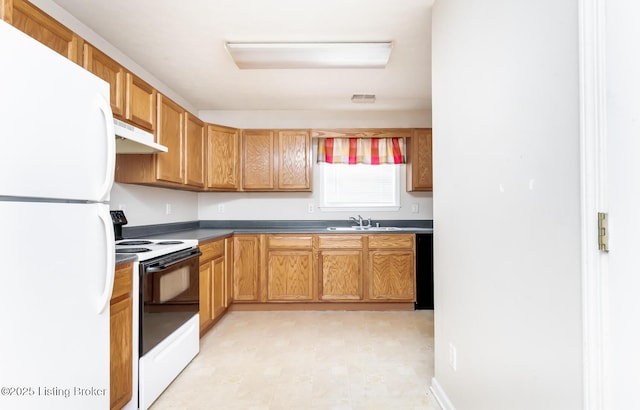 kitchen with a sink, freestanding refrigerator, under cabinet range hood, visible vents, and range with electric stovetop