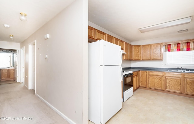 kitchen with a sink, freestanding refrigerator, under cabinet range hood, visible vents, and range with electric stovetop