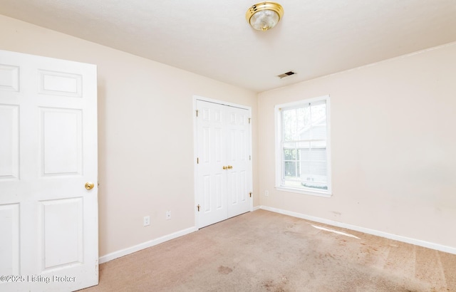unfurnished bedroom with baseboards, carpet flooring, visible vents, and a closet