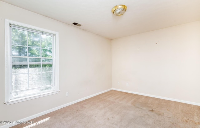 empty room featuring visible vents, baseboards, and light carpet