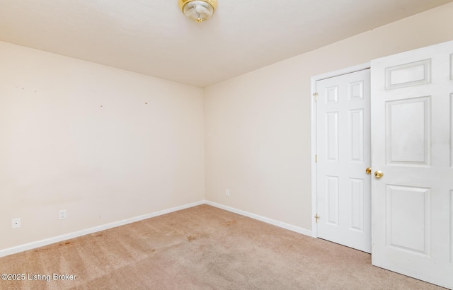 unfurnished room featuring baseboards and light carpet