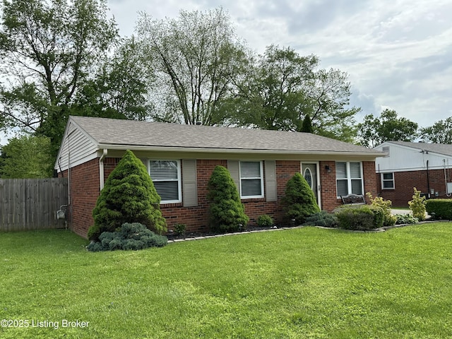 ranch-style house with brick siding, fence, a shingled roof, and a front yard