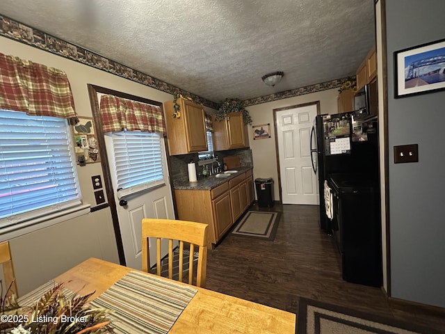kitchen featuring brown cabinetry, a textured ceiling, dark wood-style flooring, and dark countertops