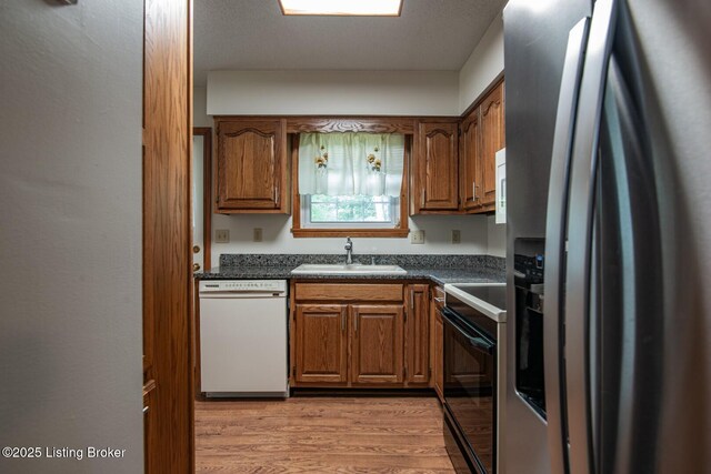 4217 Deckard School Rd, Radcliff, KY 40160 - kitchen with white dishwasher, stainless steel fridge with ice dispenser, a sink, dark countertops, and light wood-style floors